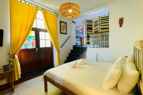 a bedroom with a bed with yellow curtains and a staircase at Ami Vine House in Cape Town