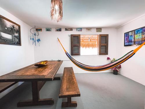 a hammock in a room with a table and benches at Beco do Preá - Kite Apartamentos e Suítes Beira Mar in Prea