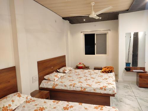 Hotel shree Sidhi vinayak في اوجاين: غرفة نوم بسريرين ومروحة سقف