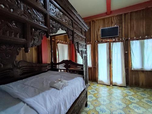 a bedroom with a large bed with a wooden frame at Omah Joglo Sukorejo RedPartner in Sukareja
