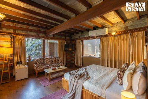 a bedroom with a bed and a couch in a room at StayVista at The Manor with Mountain View & Fireplace in Manāli