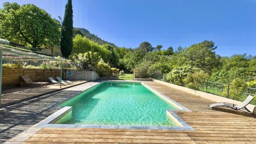 a swimming pool on a wooden deck with two chairs at Gîte dans Bastide Provençale, Piscine & Sauna in Auriol