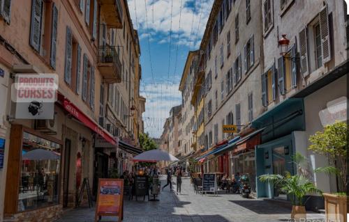 une rue avec des bâtiments et des personnes marchant dans une rue dans l'établissement Terrazzo, à Bastia