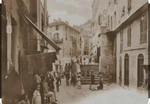 an old photo of a group of people walking down a street at Terrazzo in Bastia