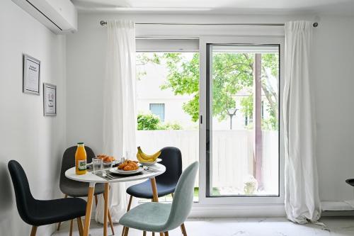 a dining room with a table and chairs and a window at Appartement Paisible Climatisé in Malakoff