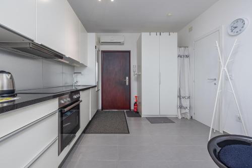 a kitchen with white walls and a brown door at See the Sea in Nin
