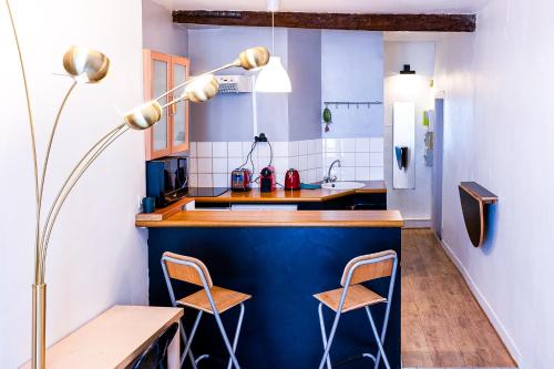une cuisine avec un comptoir bleu et deux chaises dans l'établissement Cosy Beautiful Studio Heart of Paris Saint-Germain des Prés, à Paris