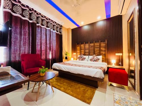 une chambre d'hôtel avec un lit et un fauteuil rouge dans l'établissement Sawan INN, à Rūpnagar