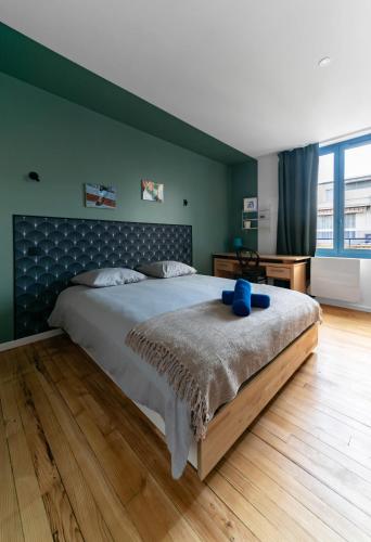 - une chambre dotée d'un grand lit avec un ours en peluche bleu dans l'établissement Le Petillat - Appartement design en centre ville, à Vichy