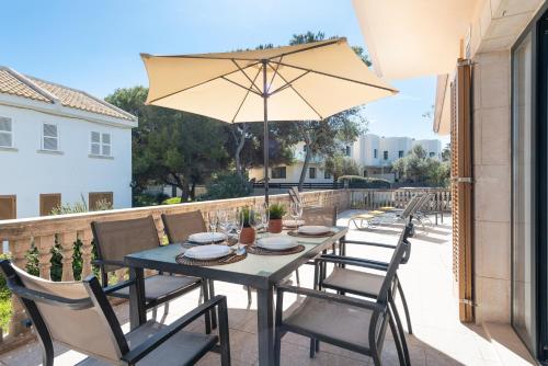 una mesa con sillas y una sombrilla en el patio en Villa LA CANTA, Muro Beach, Alcudia, en Muro