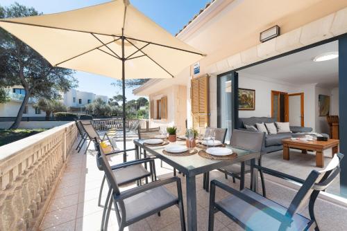un patio con mesa, sillas y sombrilla en Villa LA CANTA, Muro Beach, Alcudia, en Muro