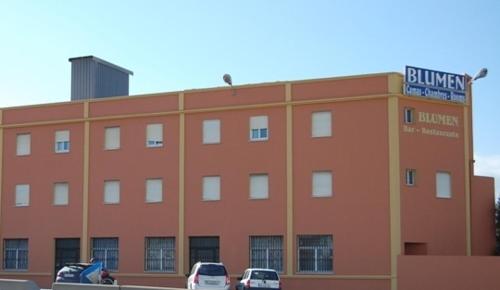 un gran edificio de ladrillo con coches estacionados frente a él en Hostal Blumen, en Algeciras