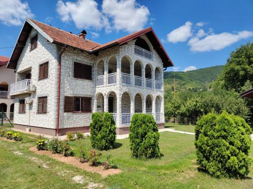 an old house with a balcony and bushes at Vila FH in Ilijaš
