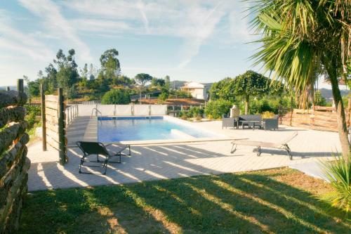 a backyard with a swimming pool and a palm tree at Quinta da Paixão - Bed & Breakfast in Pedraça