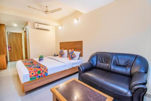 a bedroom with a bed and a leather chair at FabHotel Jansi Deluxe Gandhipuram in Coimbatore