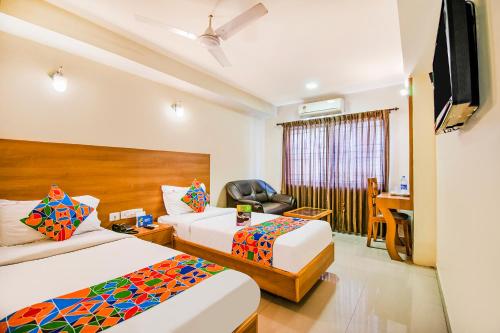 a hotel room with two beds and a desk at FabHotel Jansi Deluxe - Nr Gandhipuram Bus stand in Coimbatore