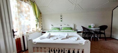 - un lit blanc dans une chambre avec une table dans l'établissement Girska Sonata Hotel & Apartments, à Mykulychyn