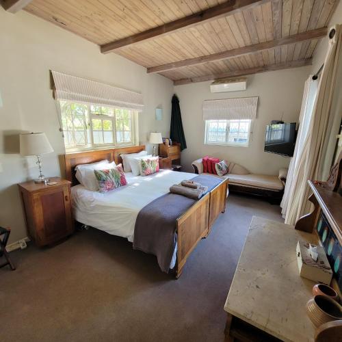 a bedroom with a large bed and a couch at AppleBee Guest Cottages in Grahamstown
