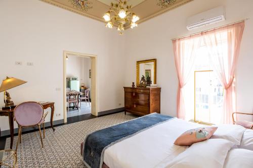 una camera con letto, scrivania e finestra di Palazzo d'Autore - Luxury Home - Ragusa Centro a Ragusa