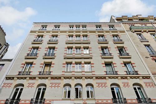 un edificio alto de ladrillo con ventanas en un lateral en Résidence moderne et Cosy avec Clim à Levallois, en Levallois-Perret