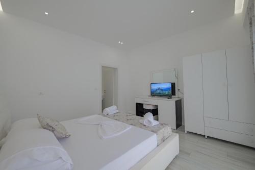 a white bedroom with two beds and a television at Vila Irdi in Ksamil