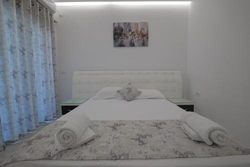 a white bedroom with a large white bed with blue curtains at Vila Irdi in Ksamil