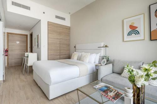 a white bedroom with a bed and a couch at Frank Porter - Studio One in Dubai