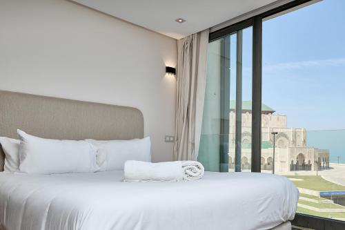 a bedroom with a white bed and a large window at Sea View & Hassan 2 Mosque By TheCasaEdition (B18) in Casablanca