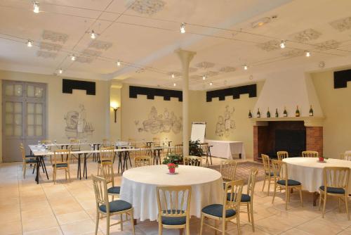 a banquet hall with tables and chairs and a fireplace at Hotel Castel Jeanson in Ay