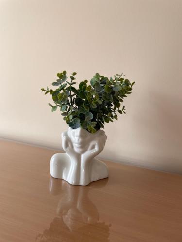 a white vase with a plant in it on a table at Sobe Sara in Šabac