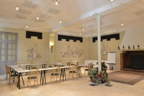 a dining room with tables and chairs and a fireplace at Hotel Castel Jeanson in Ay
