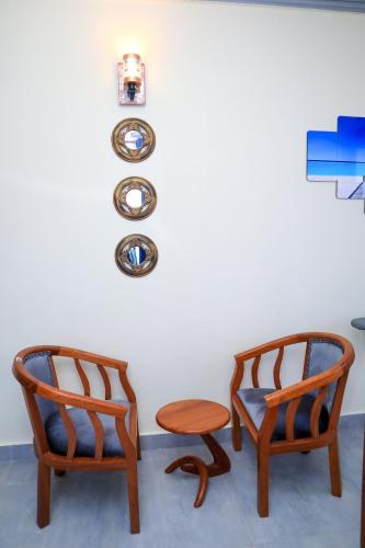 two chairs and a stool sitting next to a wall at Pavillion Suites, pazuri Homes in Nyali