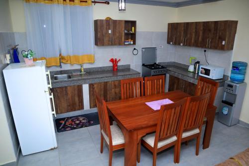 a kitchen with a wooden table and chairs and a refrigerator at Pavillion Suites, pazuri Homes in Nyali