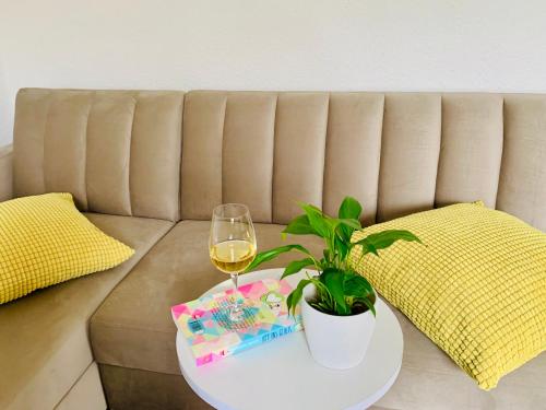 a table with a glass of wine and a plant on a couch at Ferienwohnung "Perle im Grünen" in Federow