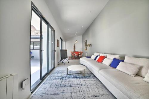 uma sala de estar com um sofá branco e uma grande janela em Villa de Rêve à La Tremblade - Piscine chauffée em La Tremblade