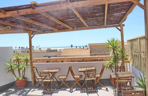 a patio with chairs and tables and a wooden pergola at Complejo La Chanca, HAB 11 in Conil de la Frontera