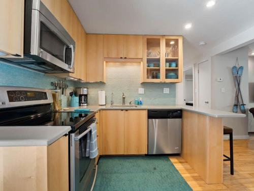 a kitchen with wooden cabinets and stainless steel appliances at Relaxing 2 Bedroom steps from Vail Resort in Vail