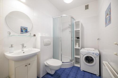 a white bathroom with a sink and a washing machine at Lapwing Apartments - Comfort in Sopot