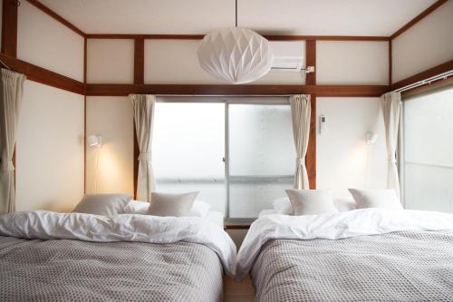 2 camas en una habitación con ventana en Saku House Jujo, en Tokio