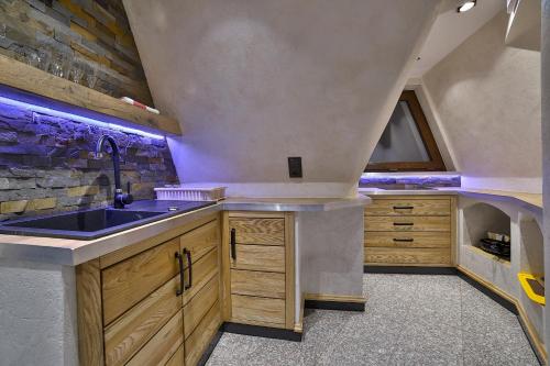 a kitchen with a sink and a stone wall at Śwarna Wynajem Pokoi in Zakopane