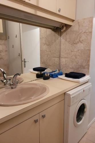 une salle de bain avec un lavabo et une machine à laver dans l'établissement Studio sur le remblai des Sables dOlonne, à Les Sables-dʼOlonne