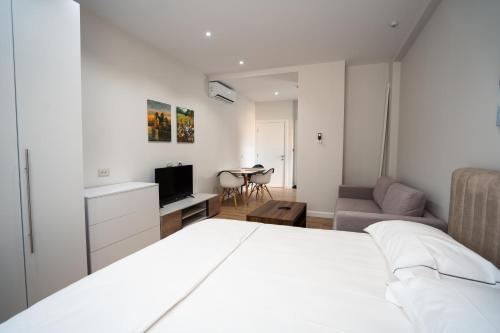 een slaapkamer met een wit bed en een woonkamer bij Tirana Elite Apartments in Tirana