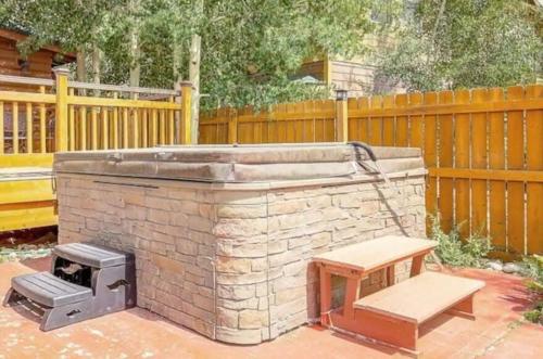 a brick barbecue with a bench next to a wooden fence at Modern 3bd cabin in Edgewater in Granby