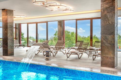 a pool with chairs and a water fountain at Dve Kule Resort & Winery in Bačinci