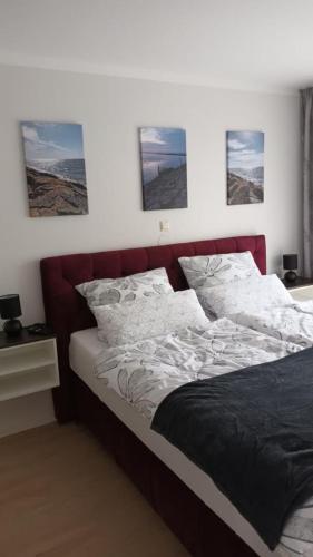 ein Bett in einem Schlafzimmer mit Bildern an der Wand in der Unterkunft NEU! Ferienwohnung Flut Ostfriesland in Marienhafe