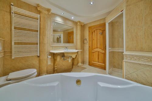 a bathroom with a tub and a toilet and a sink at Szarotka Wynajem Pokoi in Zakopane