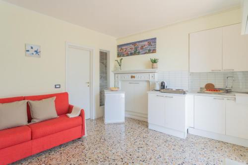 a living room with a red couch and a kitchen at Il Timone by Rent All Como in Colonno