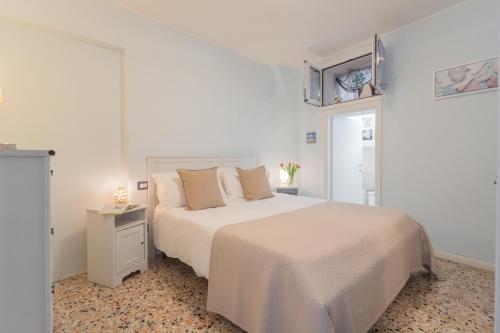a white bedroom with a white bed and a table at Il Timone by Rent All Como in Colonno