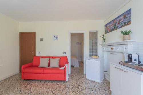 a living room with a red couch and a kitchen at Il Timone by Rent All Como in Colonno