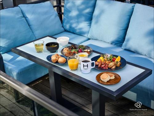 a table with two plates of food on a blue couch at Daiwa Roynet Hotel Nishi-Shinjuku PREMIER in Tokyo
